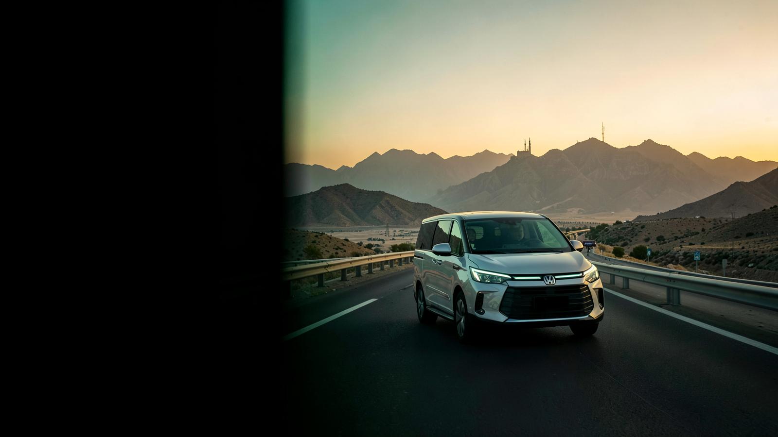 An unbranded passenger vehicle on a Saudi mountain road at sunset